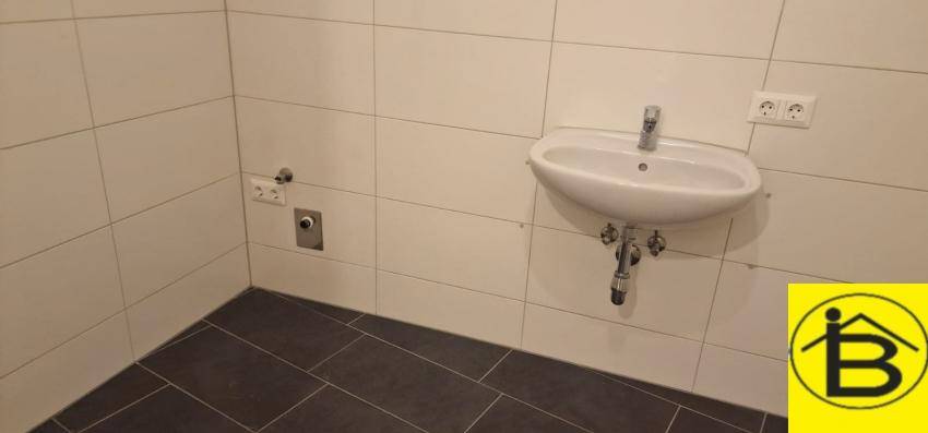 Modernes Badezimmer mit Waschbecken und weißen Fliesen, bereit für die Installation einer Dusche.