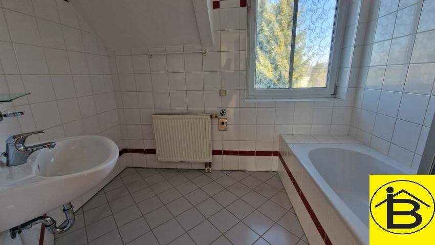 Gefliestes Badezimmer mit Badewanne, Waschbecken und Fenster, in gutem Zustand.