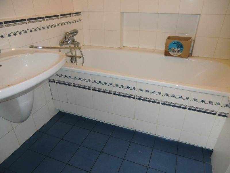Badezimmer mit Badewanne, Waschbecken, weißen Wandfliesen und blauen Bodenfliesen.