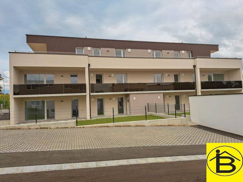 Ansicht der modernen Wohnanlage mit Balkonen und privaten Gartenbereichen im Erdgeschoss.