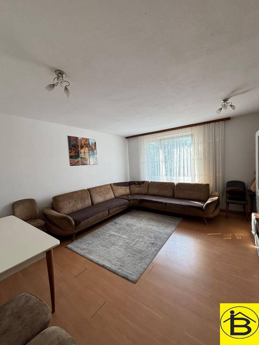 Gemütliches Wohnzimmer mit großem Ecksofa, hellem Holzboden und natürlichem Lichteinfall.