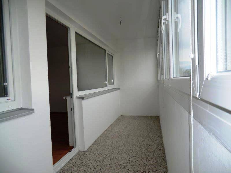 Verglaste Loggia mit hellem Boden und Fenstern, die zusätzlichen Wohnraum bietet.