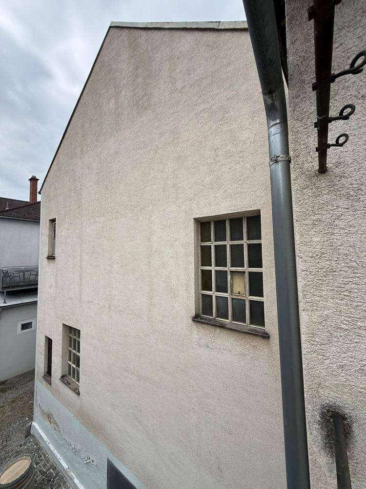 Seitenfassade eines Gebäudes mit einem Fenster und einfacher Putzstruktur.