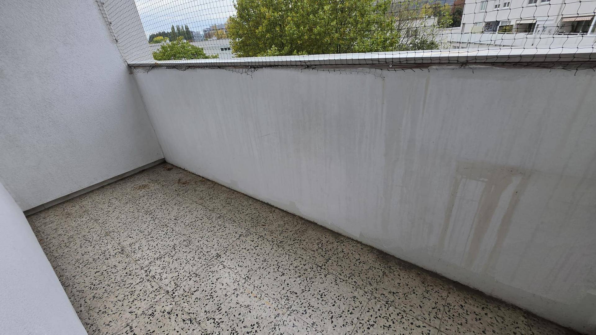 Kleiner Balkon mit Fliesenboden und Schutznetz, bietet einen Blick auf die Umgebung.