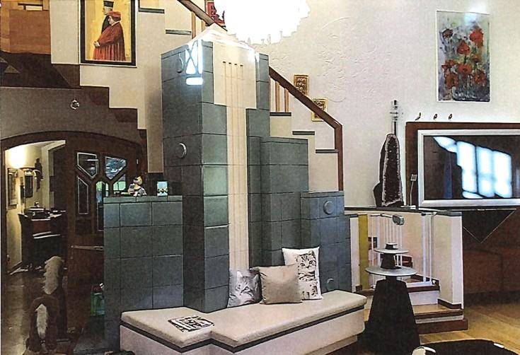 Wohnzimmer mit modernem Kachelofen, Treppe und Kunstwerken an den Wänden.