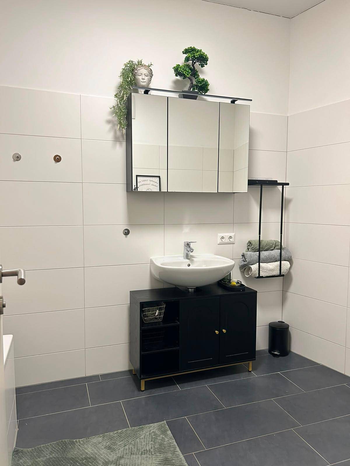 Badezimmer mit modernem Waschbeckenunterschrank, Spiegelschrank und weißen Wandfliesen.