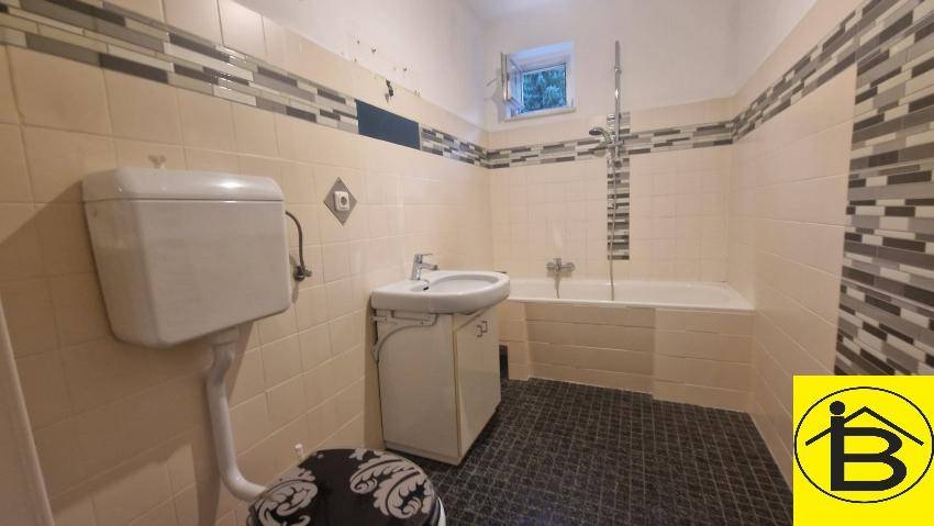 Badezimmer mit Badewanne, Dusche, WC und Fliesen in Beige und Grau.
