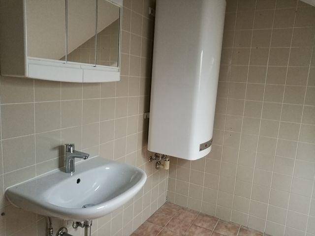 Badezimmer mit Waschbecken, Spiegelschrank und beigefarbenen Wand- und Bodenfliesen.