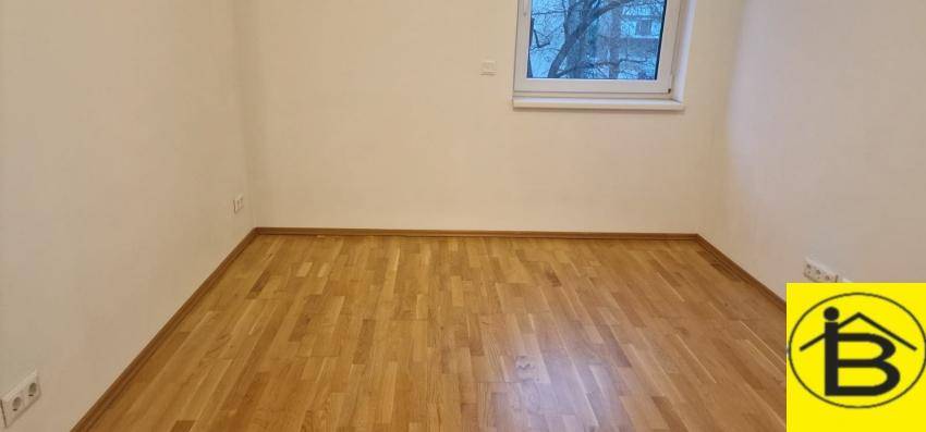 Gemütliches Schlafzimmer mit Holzboden und einem Fenster, das eine ruhige Atmosphäre schafft.