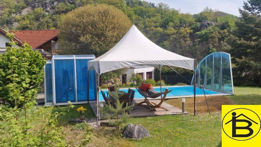 Großer Gartenbereich mit Swimmingpool, Sonnensegel und Liegeflächen.