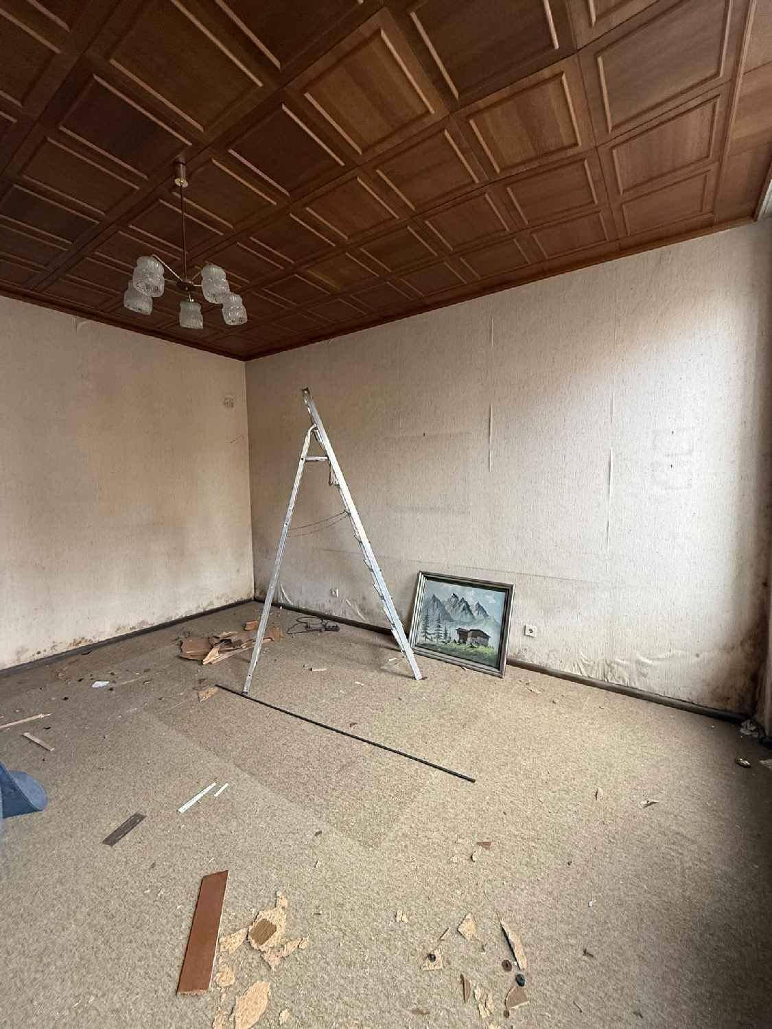 Zimmer mit Holzdecke und Teppichboden, das auf eine Renovierung wartet.