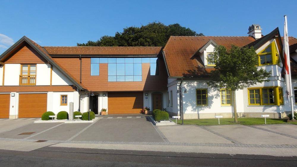 Gebäudefassade mit gelben Fensterrahmen und einem modernen Anbau mit großen Glasflächen.
