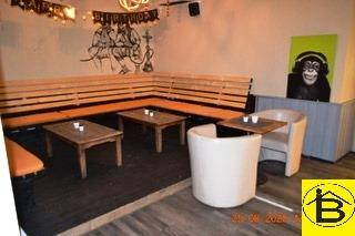 Gemütlicher Loungebereich mit Holzbänken, kleinen Tischen und kreativer Wanddekoration.