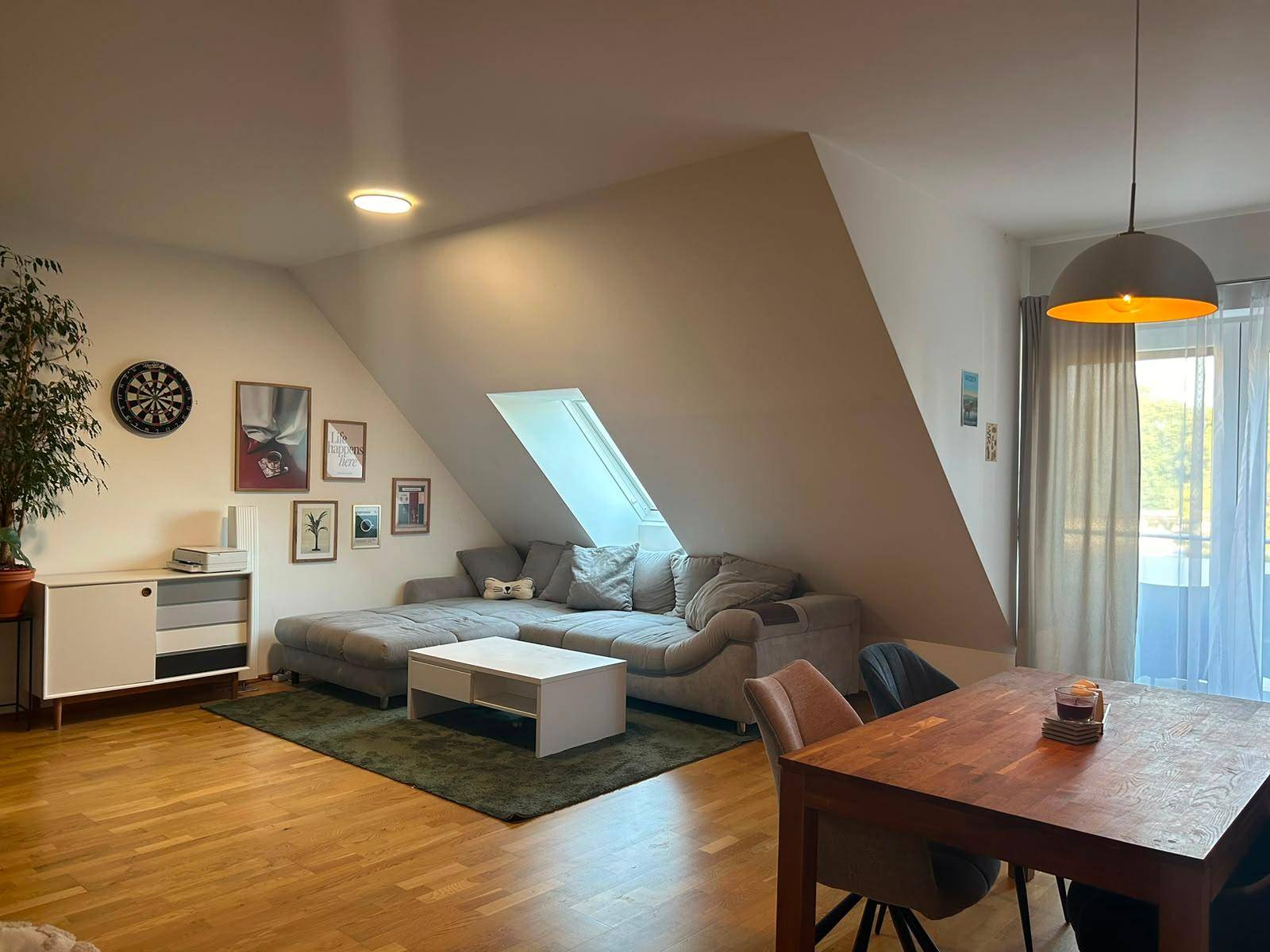 Gemütliches Wohnzimmer mit großem Sofa, Couchtisch und einem Dachfenster für viel Tageslicht.