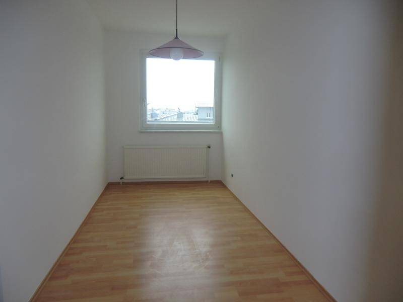 Helles Zimmer mit Laminatboden und einem Fenster, das einen Blick auf die Umgebung bietet.