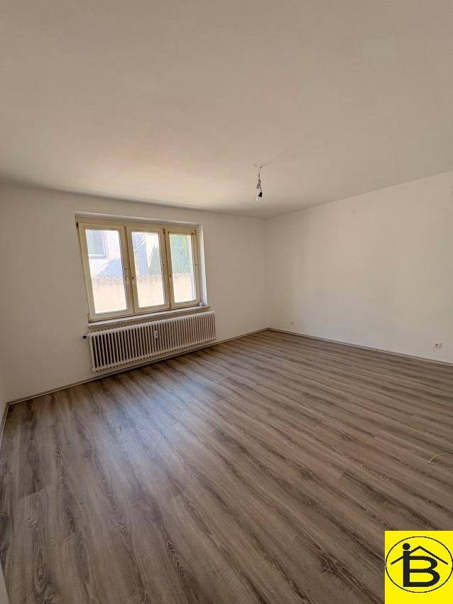 Geräumiges Zimmer mit neuem Laminatboden und großem Fenster, das viel natürliches Licht hereinlässt.