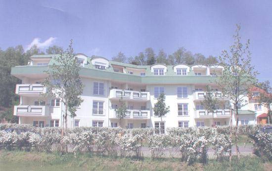 Mehrfamilienhaus mit mehreren Balkonen und grüner Dachgestaltung in einer ruhigen Wohngegend.