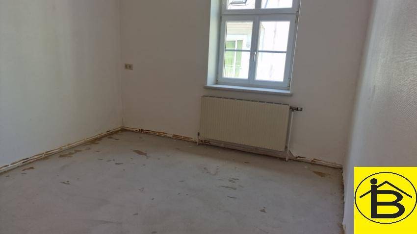 Kleinerer Raum mit einem Fenster und Heizkörper, der auf eine neue Gestaltung wartet.
