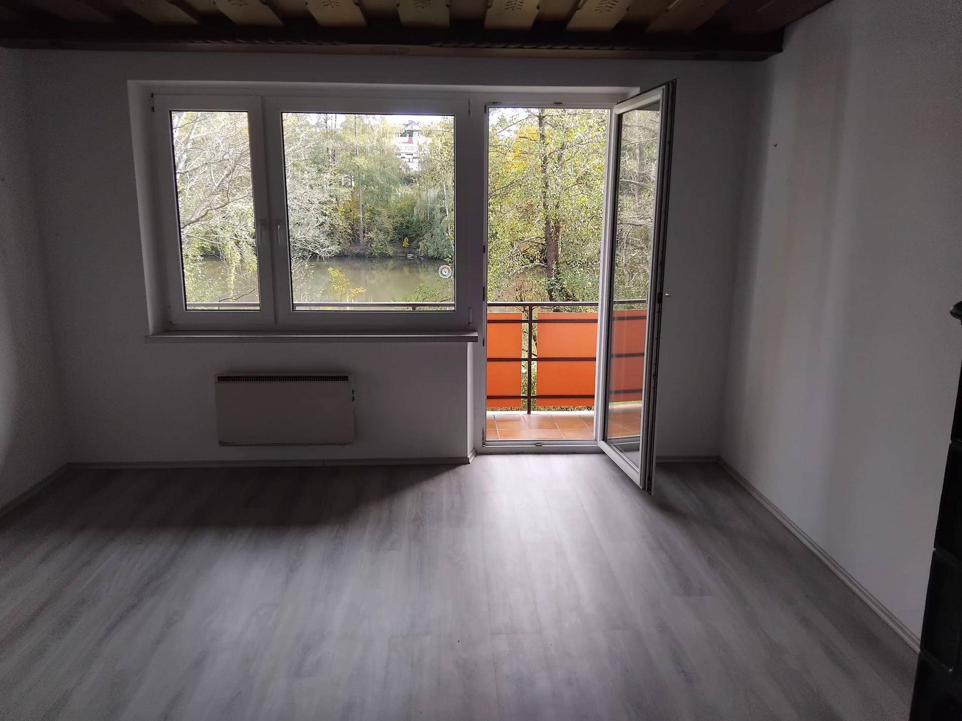Heller Raum mit großem Fenster, Zugang zu einem kleinen Balkon und Blick auf das Wasser.