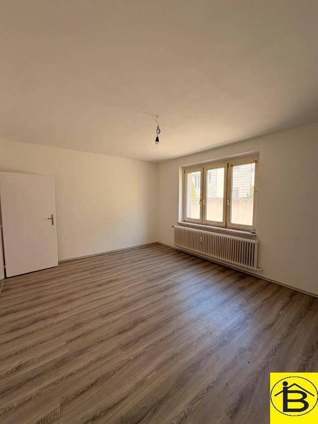 Helles Wohnzimmer mit modernem Laminatboden und weiß gestrichenen Wänden, bereit zum Einzug.