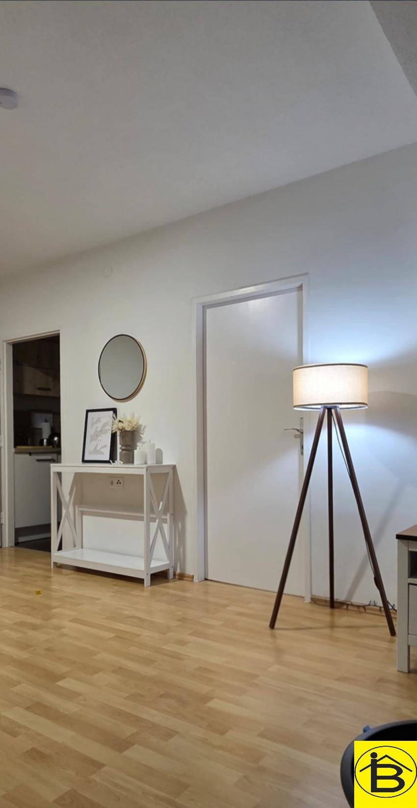 Heller Flur mit Holzboden, weißer Konsole, dekorativem Spiegel und Stehlampe.