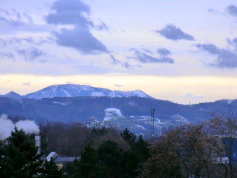 Malerischer Blick auf schneebedeckte Berge und eine weite Landschaft unter bewölktem Himmel.