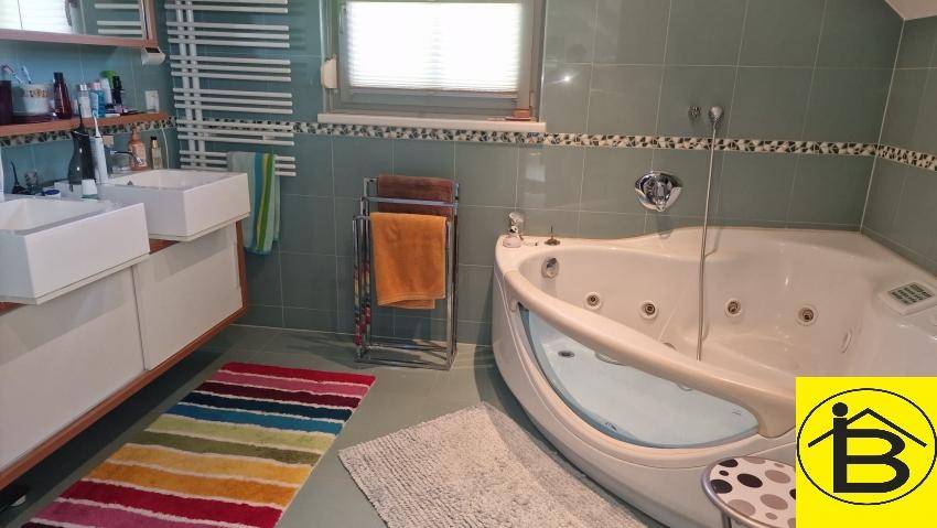 Badezimmer mit Eck-Whirlpool, Doppelwaschbecken und beheiztem Handtuchhalter.