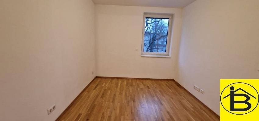 Ruhiges Schlafzimmer mit Holzboden und einem Fenster, das Tageslicht hereinlässt.