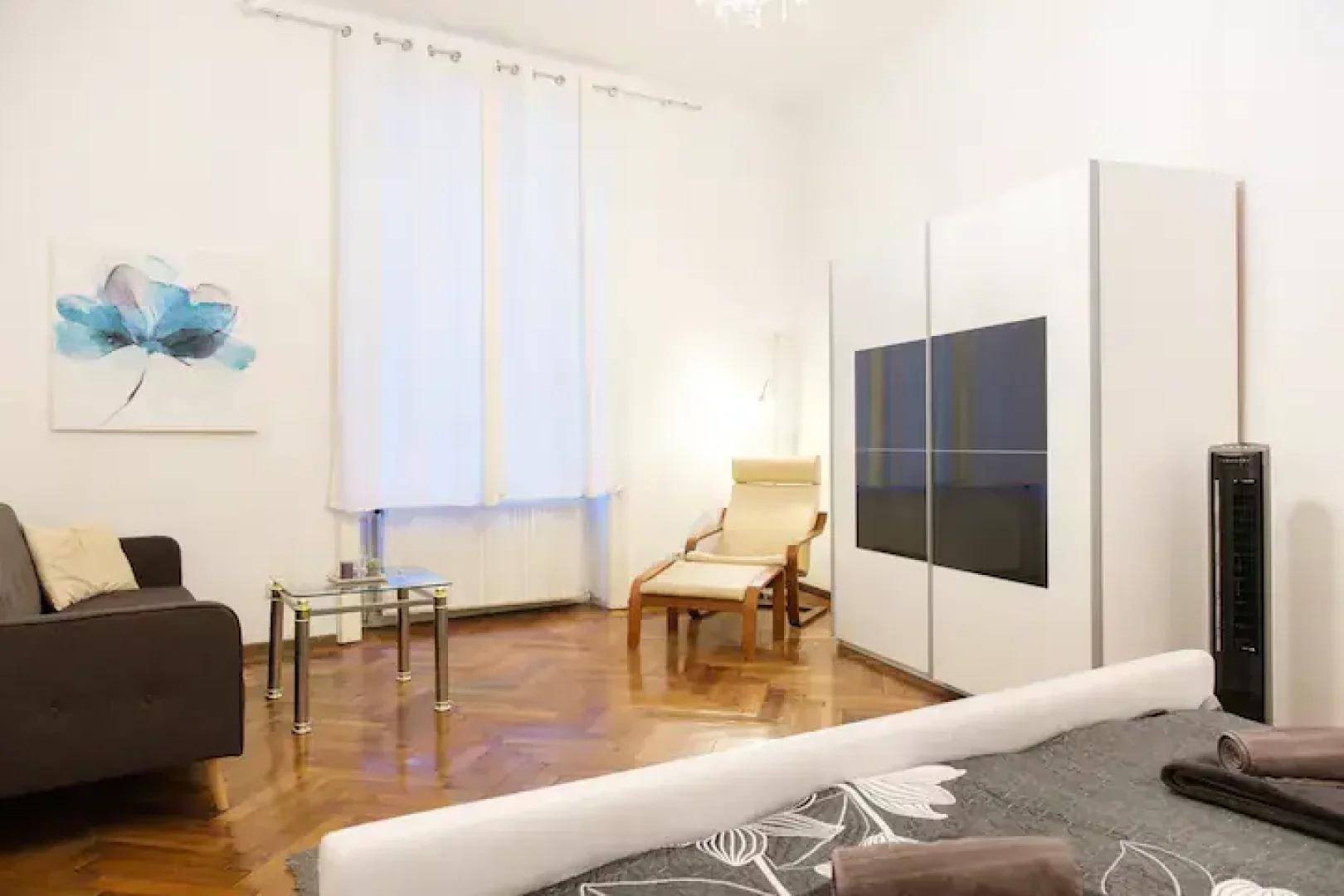Schlafzimmer mit Parkettboden, Kleiderschrank und Liegestuhl, bietet eine entspannte Atmosphäre.