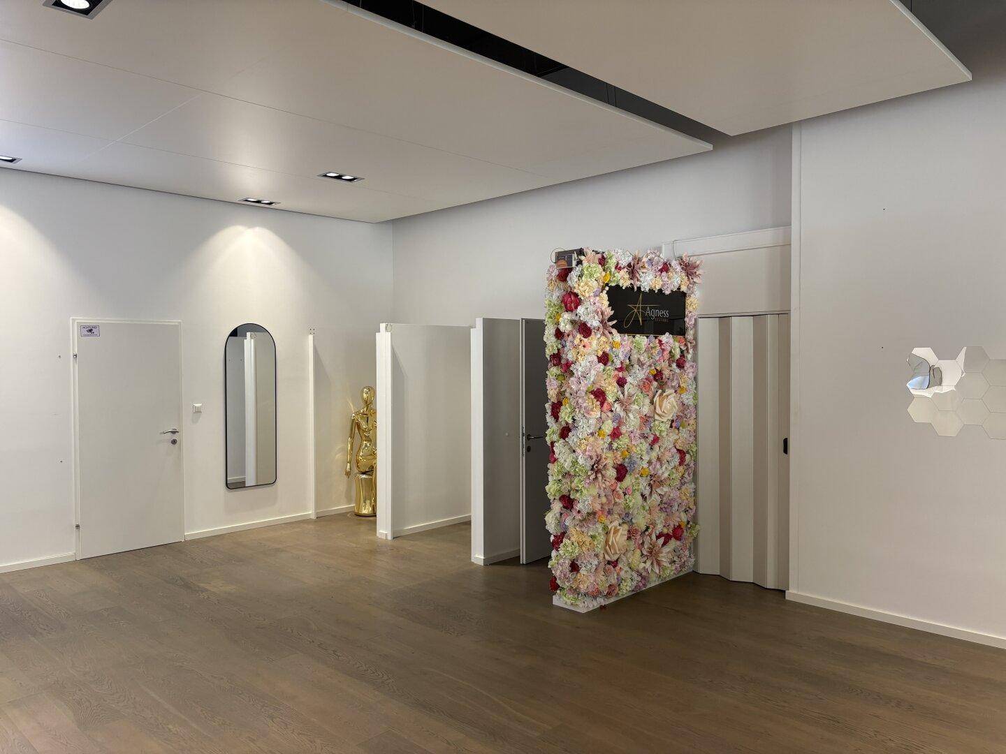Geräumiger Verkaufsraum mit Umkleidekabinen und einer auffälligen Blumenwand als Dekorationselement.