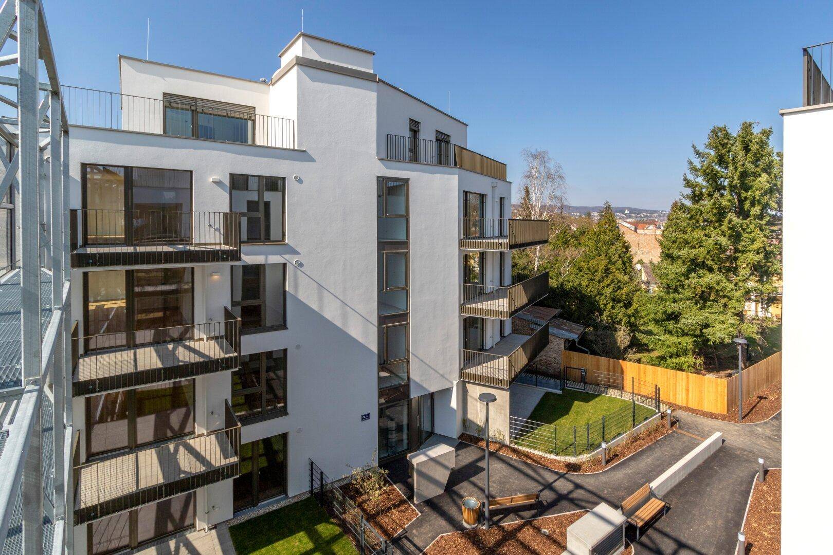 Außenansicht eines modernen Wohnkomplexes mit mehreren Balkonen und Blick auf die Umgebung.