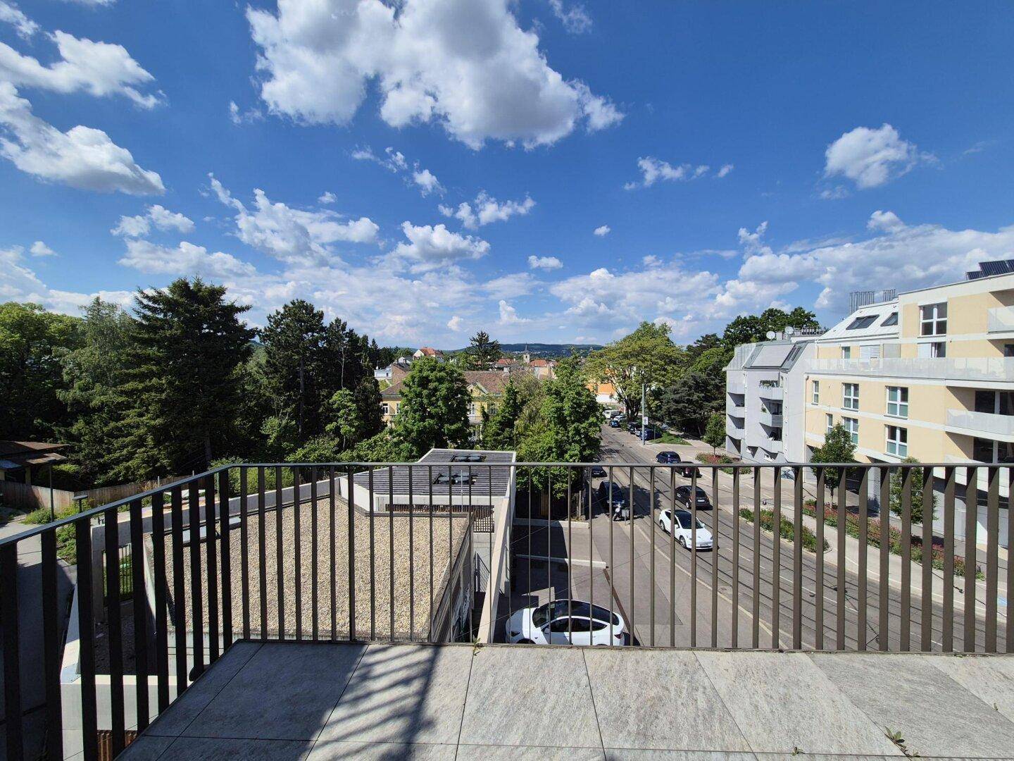 Geräumige Dachterrasse mit Fliesenboden und weitem Blick über die Stadt und die grüne Umgebung.