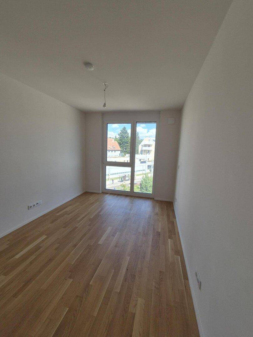 Helles Schlafzimmer mit Eichenparkettboden und großen Fenstern, die viel Tageslicht hereinlassen.