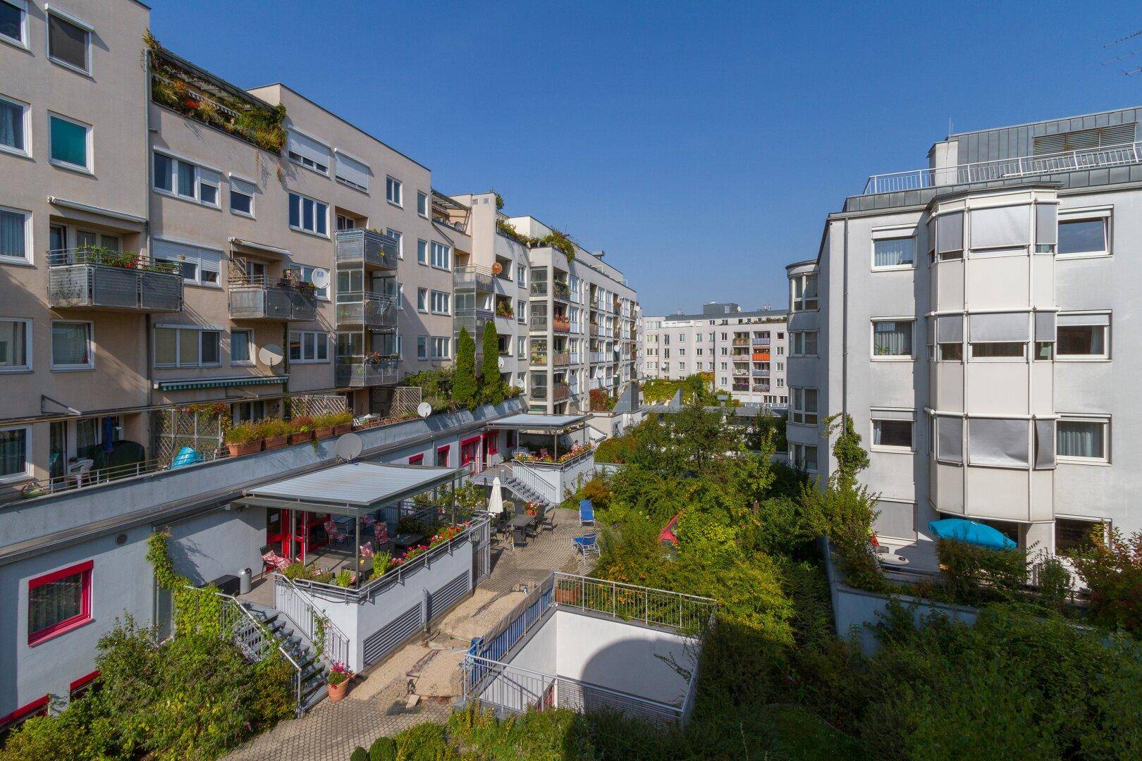 Erhöhte Ansicht eines Wohnkomplexes mit begrünten Innenhöfen und vielen Balkonen.