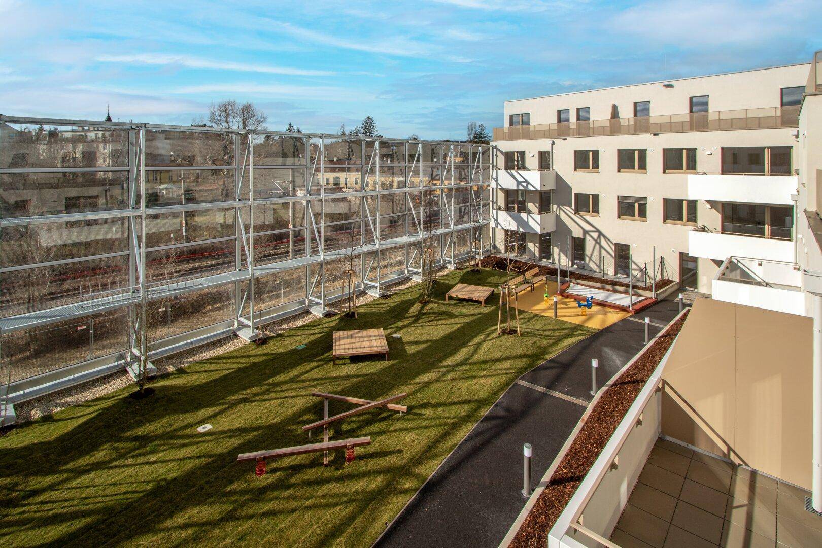 Weitläufiger Innenhof mit Spielplatz und Rasenfläche, umgeben von der modernen Wohnanlage.