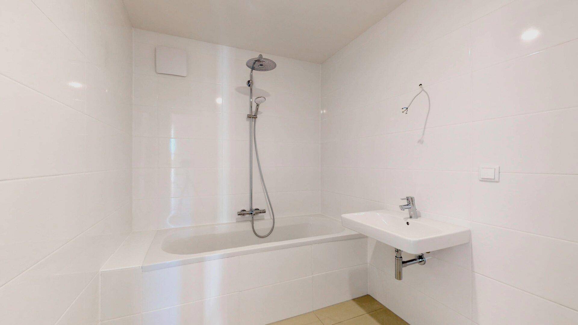 Modernes Badezimmer mit Badewanne, Duschfunktion und weiß gefliesten Wänden.