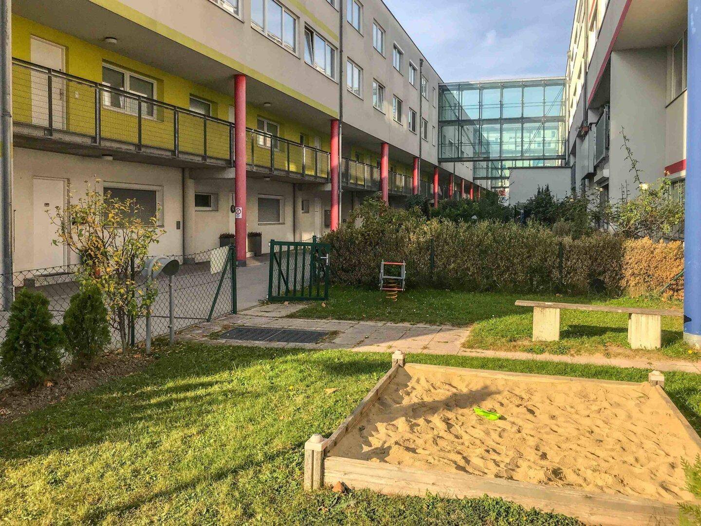 Gemeinschaftlicher Innenhof mit Sandkasten, Rasenfläche und Sitzgelegenheiten, ideal für Familien.
