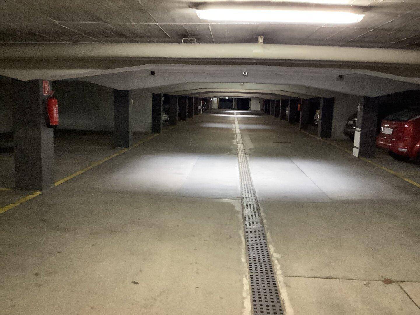 Geräumige Tiefgarage mit Betonboden, klarer Beleuchtung und markierten Parkplätzen.