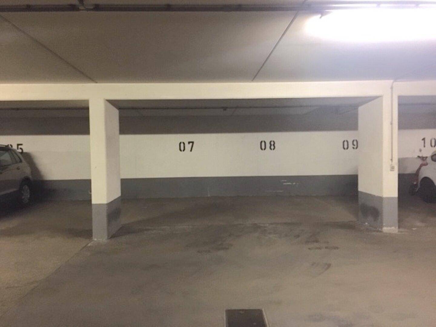 Geräumiger Tiefgaragenstellplatz mit klar nummerierten Parkbuchten und robustem Betonboden.