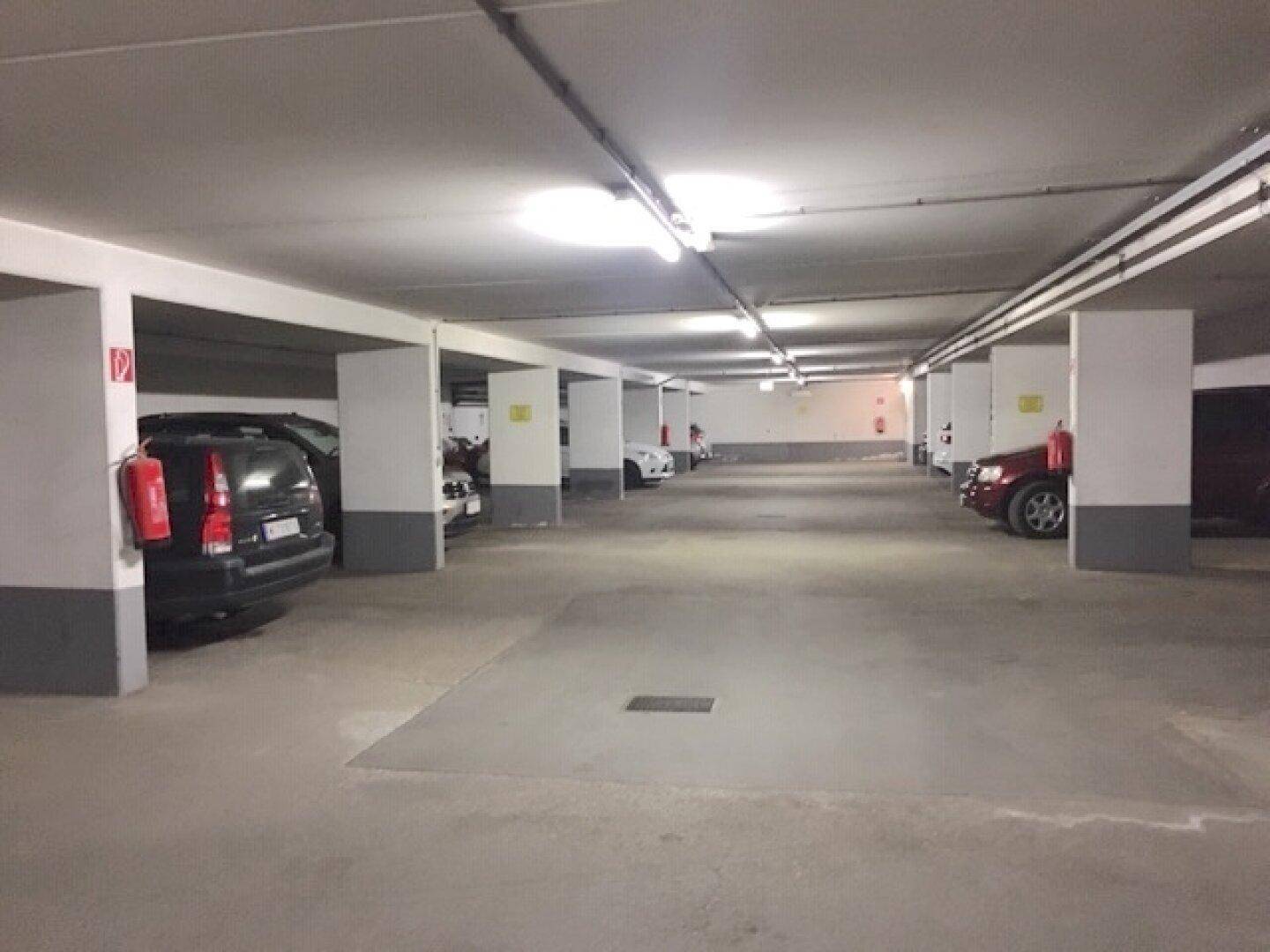 Lange Reihe von Parkplätzen in der Tiefgarage, ausgestattet mit Brandschutzvorrichtungen an den Säulen.