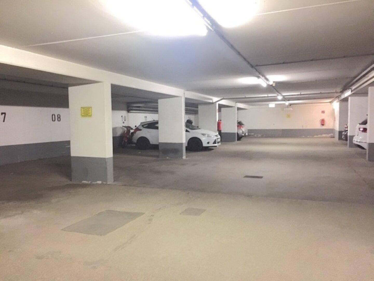 Helle Tiefgarage mit nummerierten Stellplätzen und sauberem Betonboden, bietet ausreichend Parkmöglichkeiten.
