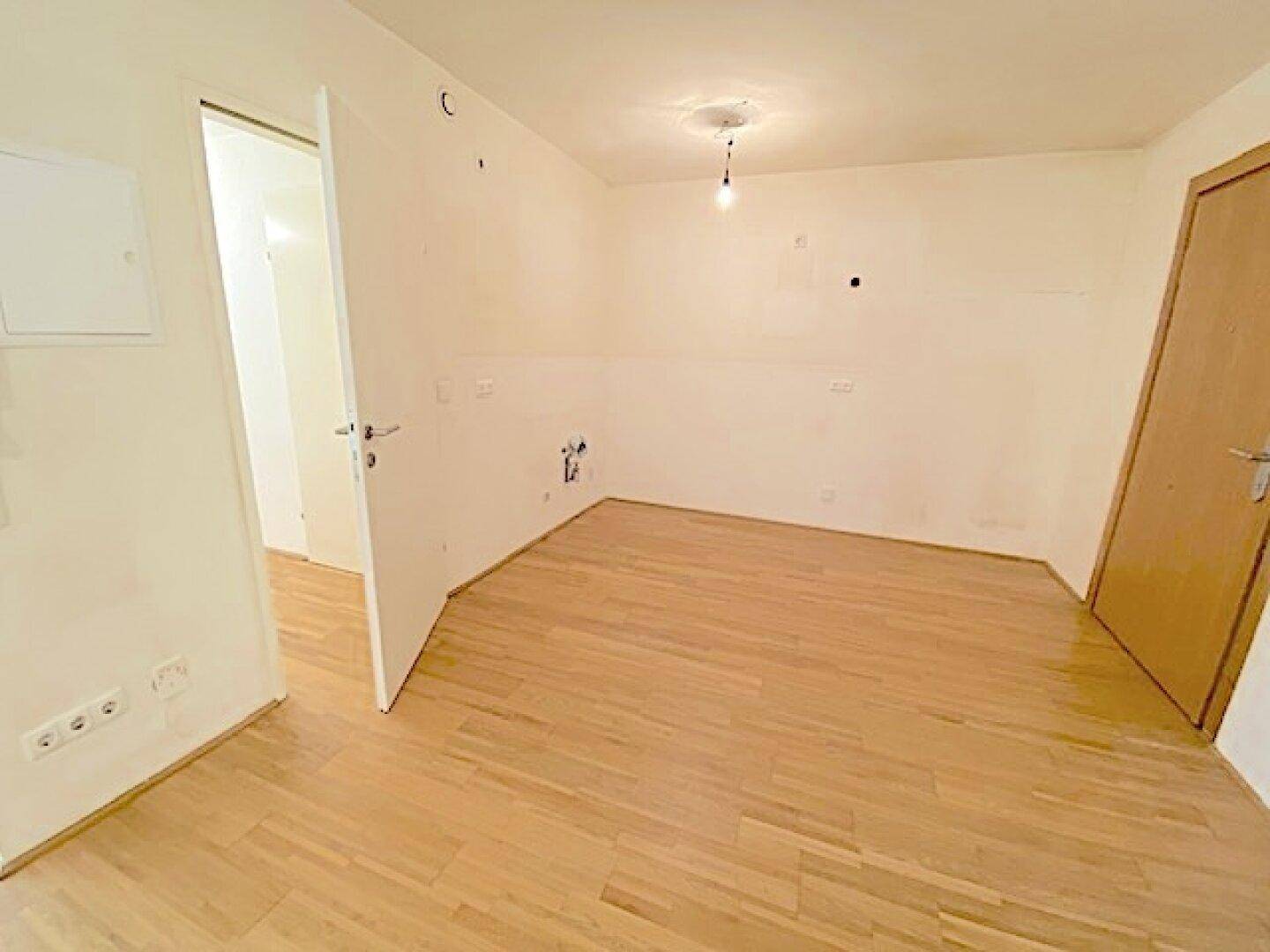 Unmöblierter Raum mit hellem Holzboden und weißen Wänden, bereit zur individuellen Gestaltung.