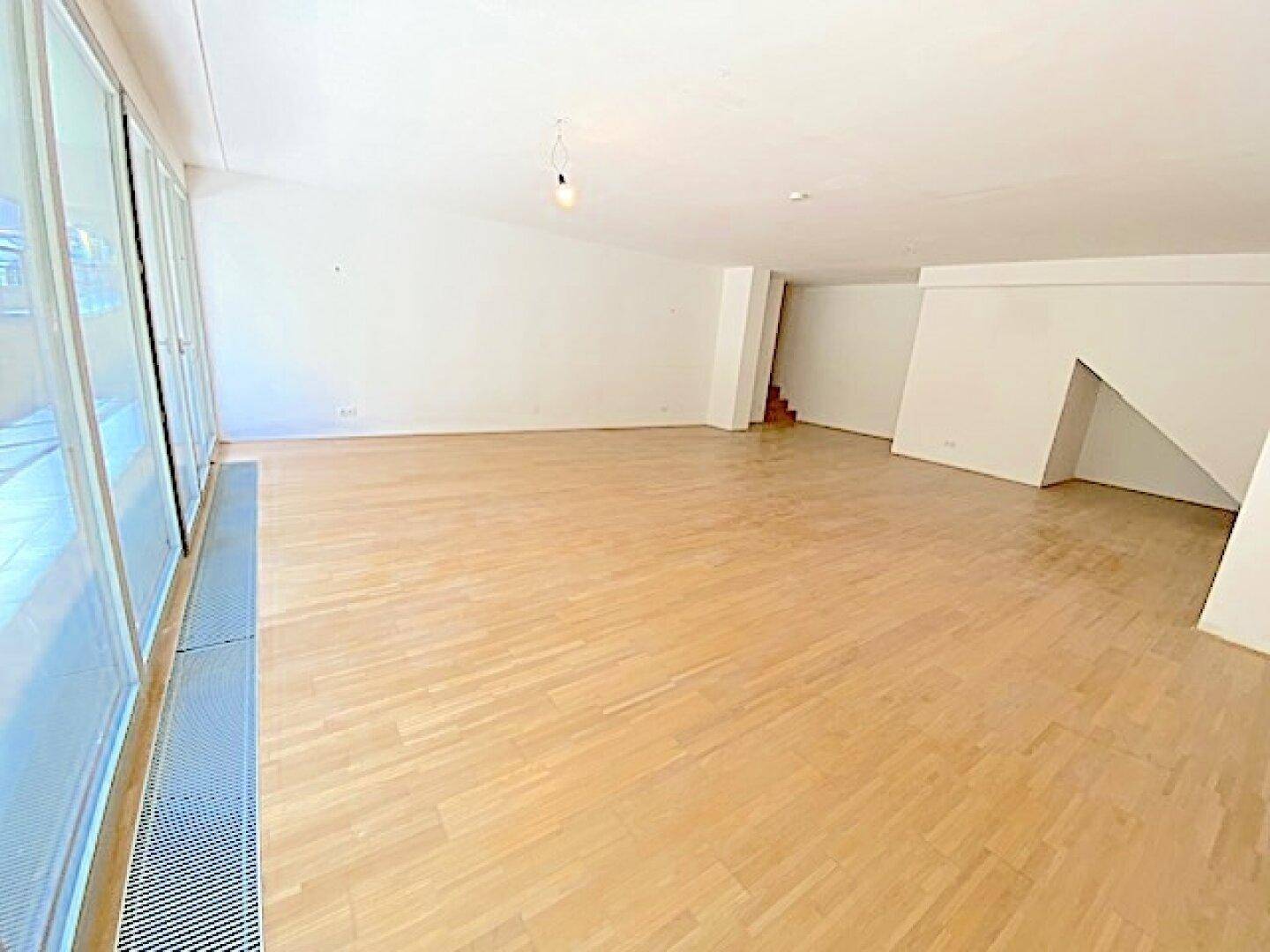 Heller und geräumiger Wohnbereich mit Holzboden und einer architektonisch interessanten Treppenkonstruktion.