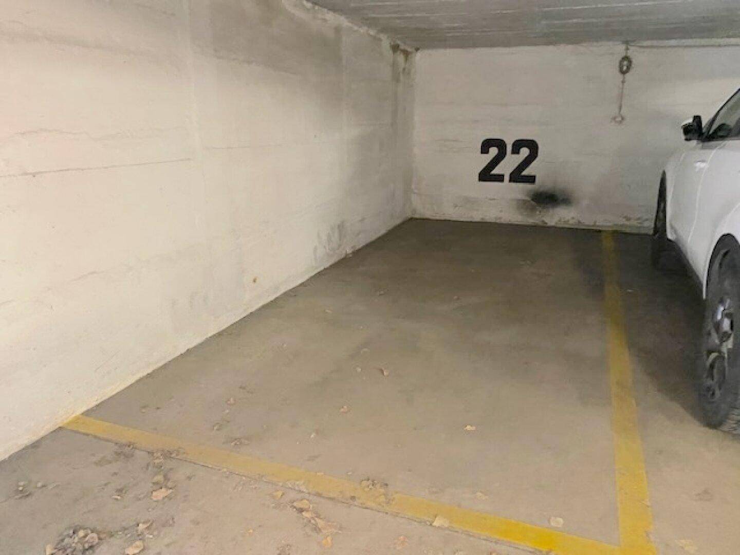 Einzelner Tiefgaragenstellplatz Nummer 22 mit gelber Markierung und einem parkenden Auto.