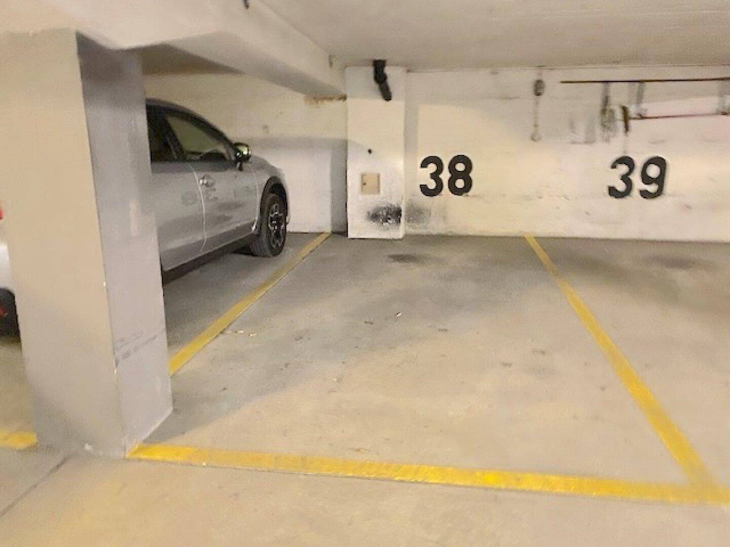 Tiefgaragenstellplätze 38 und 39 mit einem geparkten Fahrzeug und gelben Bodenmarkierungen.
