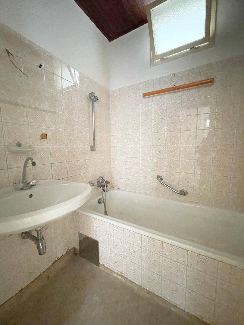 Badezimmer mit hellrosa Fliesen, Badewanne, Waschbecken und einem kleinen Fenster.