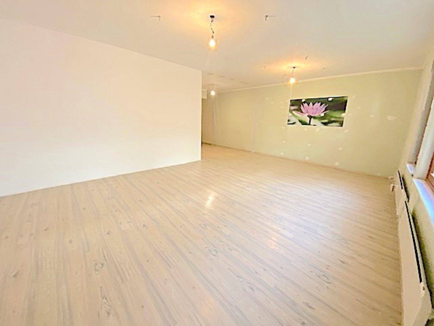 Heller Raum mit Laminatboden und einer Wanddekoration, die eine Lotusblume darstellt.