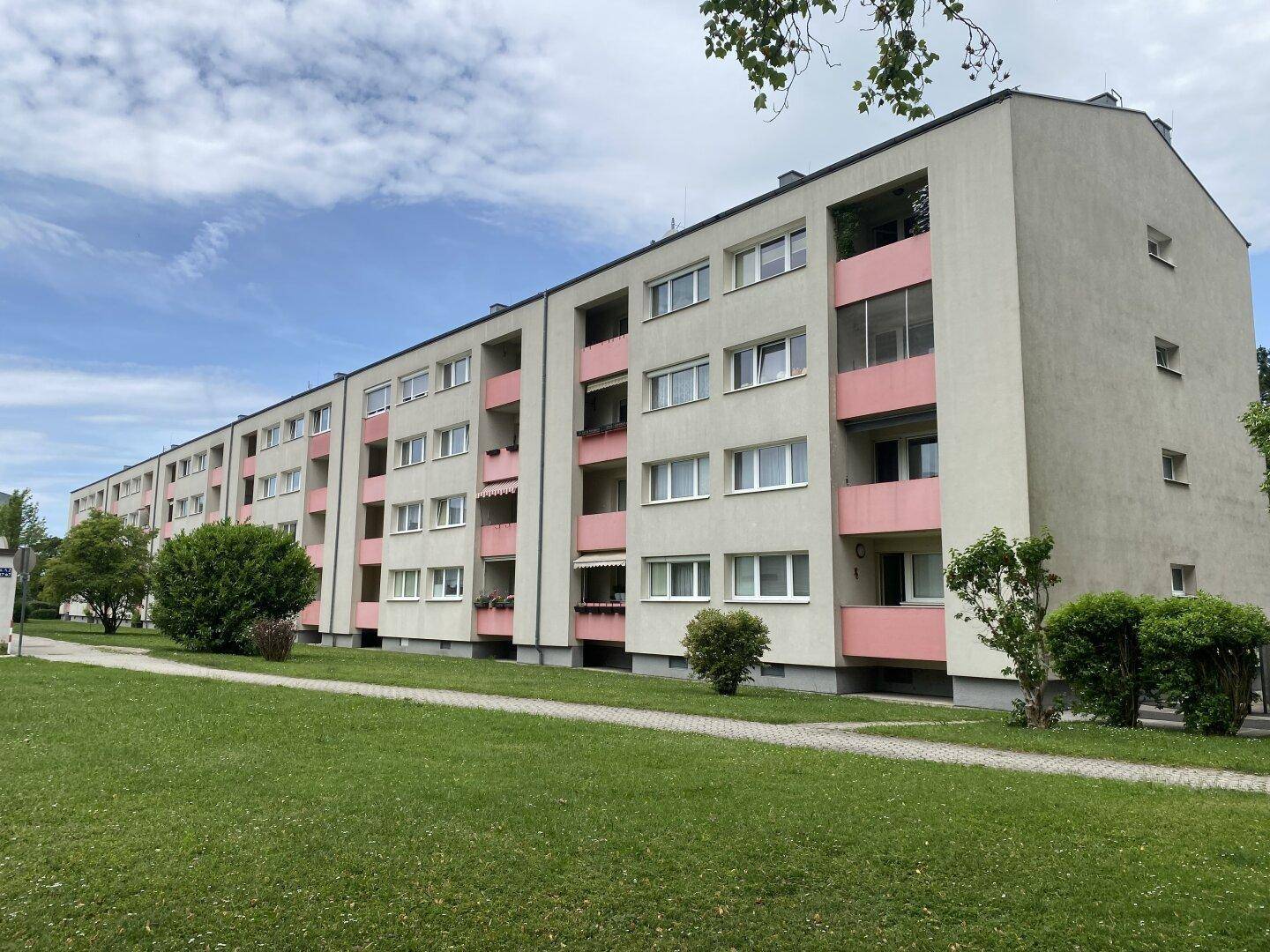 Mehrfamilienhaus mit gepflegten Grünflächen und Balkonen in einer ruhigen Wohngegend.