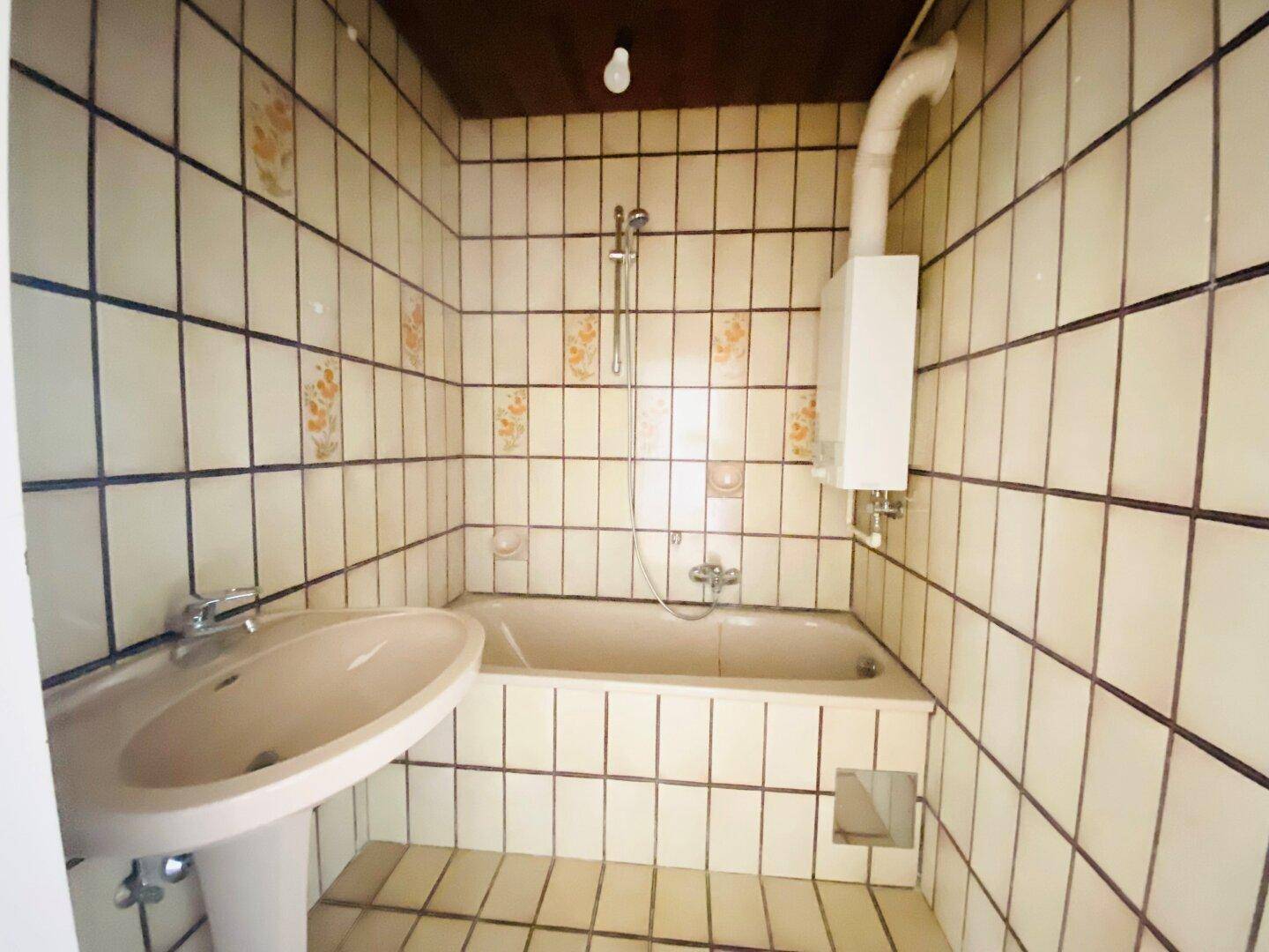 Badezimmer mit Badewanne, Duschfunktion und Waschbecken im 80er-Jahre-Stil.