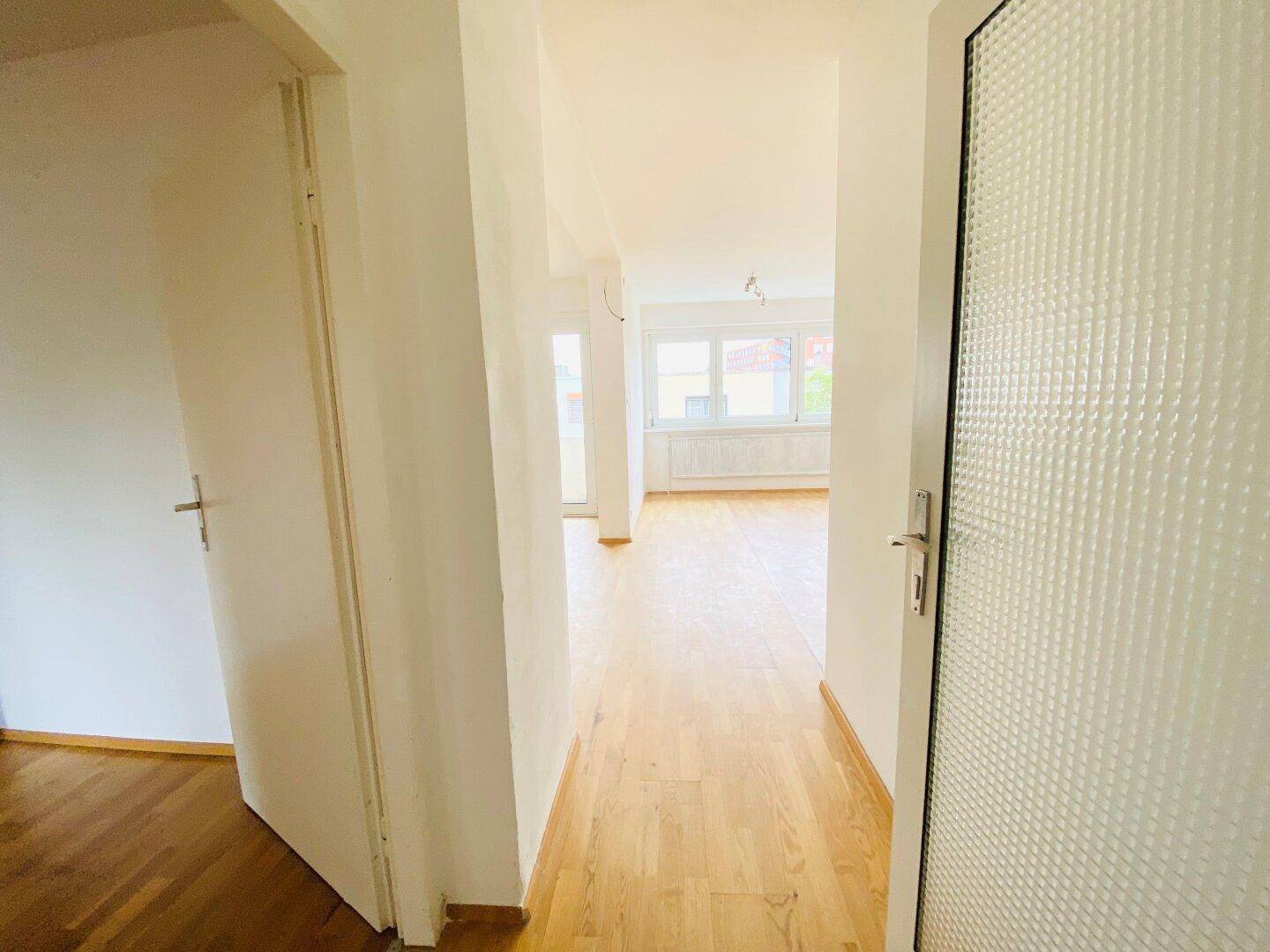 Eingangsbereich mit Parkettboden, der einen Blick in den hellen Wohnbereich ermöglicht.